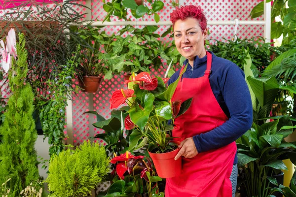 Mutlu kadın çiçekçi, düzenlemeler yapma ve kameraya gülümseyerek. küçük işletme Çiçekçi dükkanı sahibi.