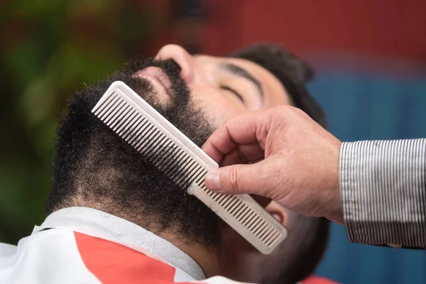 Kapper maken baard haitstyle met behulp van kam bij Barber Shop. — Stockfoto
