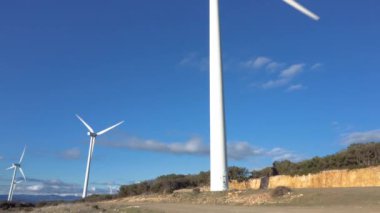 Mavi gökyüzü arka planında rüzgar enerjisi türbinleri, sürdürülebilir ekolojik enerji üretimi.