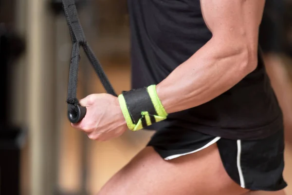 Jonge fit gespierde man close up doen triceps pull down touw uitbreiding oefening in modern fitnesscentrum. — Stockfoto