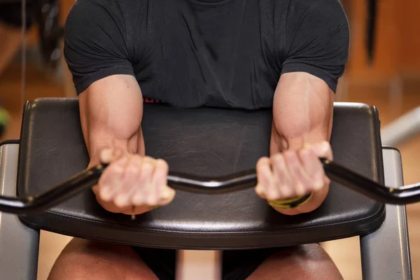 Knappe gespierde man doet biceps tillen barbell op Bank in een sportschool. — Stockfoto