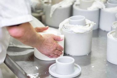 Çalışan kadın çiğ peyniri kalıba döküyor.