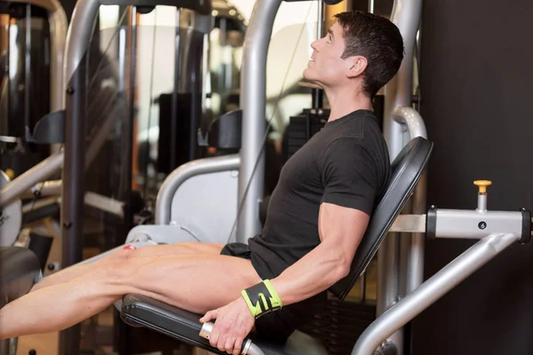 Handsome strong man performed leg press workout in the gym. — Stock Photo, Image
