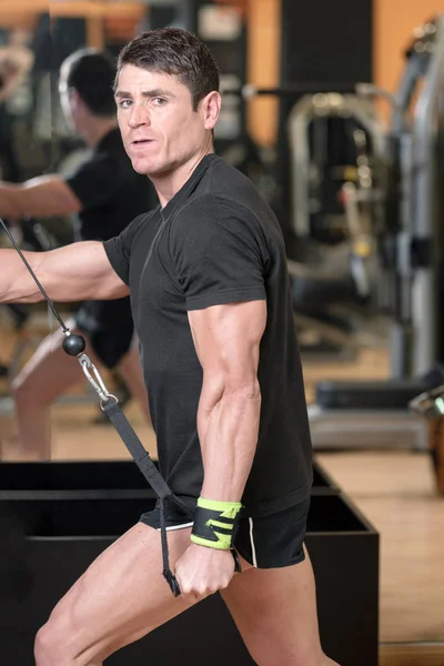 Young fit muscular man close up doing triceps pull down rope extension exercise in modern fitness center. — Stock Photo, Image
