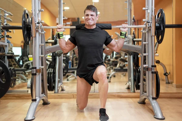 Sport, bodybuilding, levensstijl en mensen concept - jonge man met barbell doen squats in gym. — Stockfoto