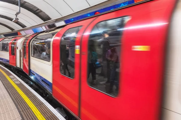 Quai du métro londonien. Avertissement peint sur le sol. Train passant par là . — Photo
