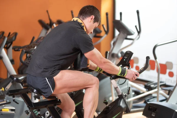 Gespierde man fietsen in de sportschool, oefenen benen doen cardio workout fietsen, Spinning klasse. — Stockfoto