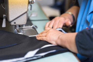 Terzi bir dikiş makinesinde giysi diker. Tekstil fabrikası.