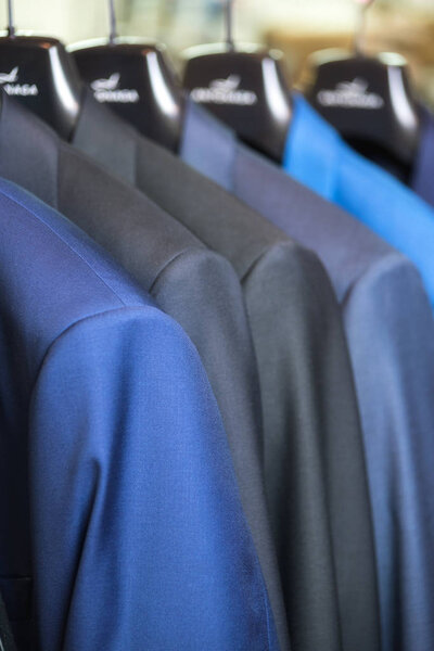 close up luxurious style gentlemen suit row, hanging in a closet.