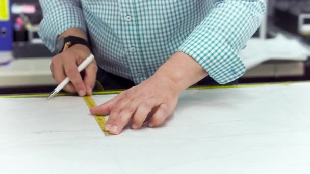 Mãos de alfaiate marcam desenho em papel artesanal para fazer padrões . — Vídeo de Stock