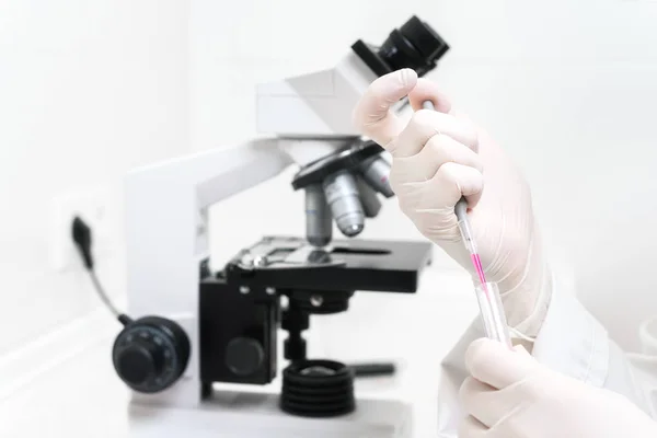 Scientist Filling Test Tube With Pipette In Laboratory. Close up view of a female scientist filling test tube with pipette by microscope in the laboratory. — Stock Photo, Image