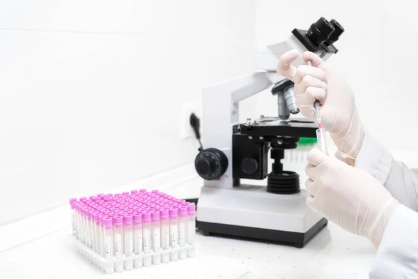 Scientist Filling Test Tube With Pipette In Laboratory. Close up view of a female scientist filling test tube with pipette by microscope in the laboratory. — Stock Photo, Image