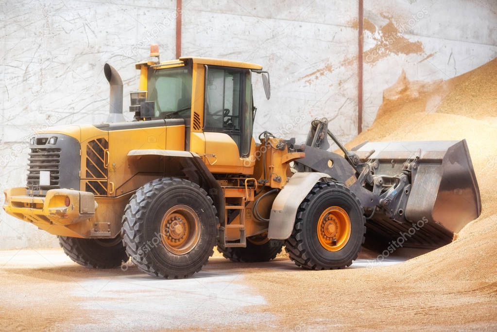 Wheel loader, excavator loading sand at construction site.