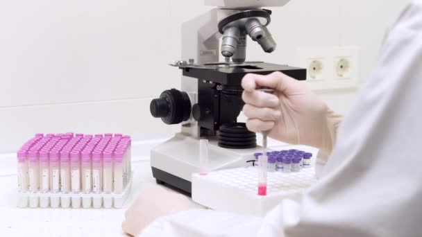 Medicinskt test i laboratorium, vetenskapsman med hjälp av en mikropipett i ett laboratorium. Injicera vätska i ett rör. — Stockvideo