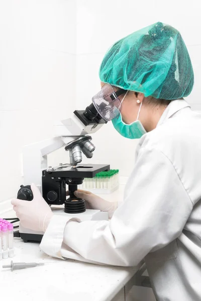 Young female scientist in modern laboratory, using microscope. — 스톡 사진