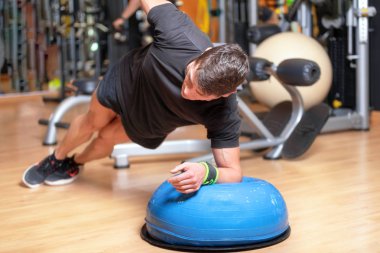 Vücut geliştirme eğitiminin bir parçası olarak topa egzersiz yaptıran genç bir atlet.