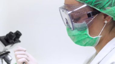 Laboratuvarda Test Tüpünü Pipetle Dolduran Bilim Adamı. Laboratuvarda mikroskop ile test tüpünü pipetle dolduran bir kadın bilim adamının yakından görünümü.