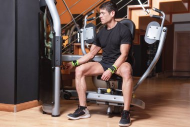 Yakışıklı kaslı adam basın göğüs makinesinde çalışmaya hazır. Göğüs egzersiz.