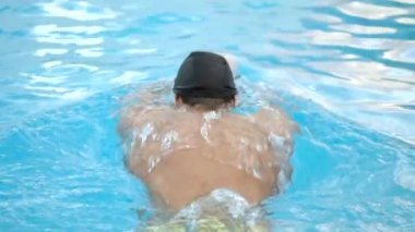 Erkek yüzücü yüzme havuzu eğitimi sırasında kelebek vuruşu yapıyor..