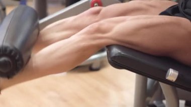 Spor salonu bacak kıvırma eğitmen çalışma kaslı bacaklar ile adam atlet yakın çekim görünümü. 