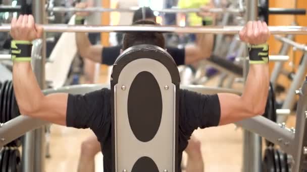 Un hombre joven en forma hace prensas aéreas en un primer plano del gimnasio por detrás . — Vídeos de Stock