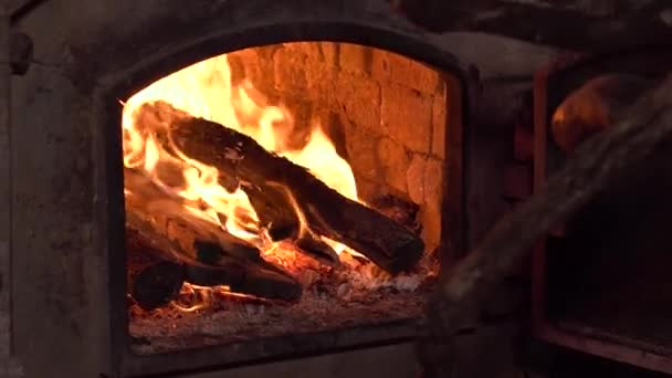 Het laden van hout naar een rustieke houtoven. Brandende vuur in de open haard. 4k-clip. — Stockvideo