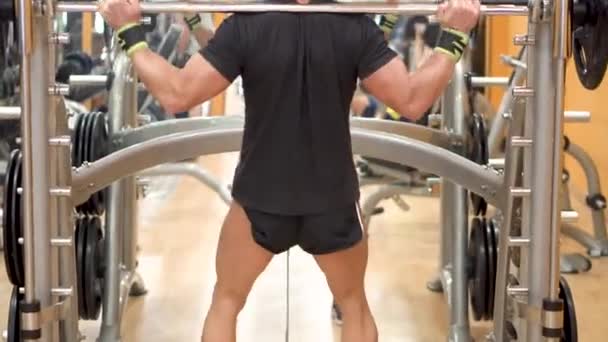 Joven con barra haciendo sentadillas en gimnasio, deporte, culturismo, estilo de vida y concepto de personas . — Vídeos de Stock