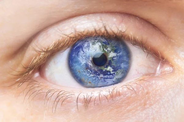 Environment conservation concept. Close up image of woman eye with earth in it. Creative composite of macro Eye with Earth as Iris. Elements of this image furnished by NASA.