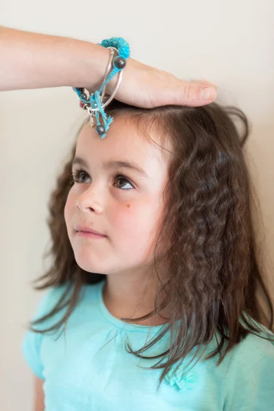 Mãe altura de medição de sua filha perto da parede branca. — Fotografia de Stock