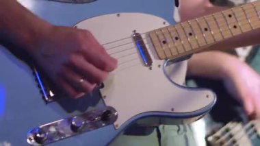 Sahnede rock grubu, konserde elektro gitar ve bas gitar çalıyor.