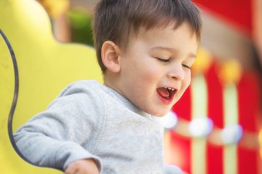  Güneşli yaz gününde oyun alanında eğlenmek sarı saçlı sevimli mutlu erkek bebek.