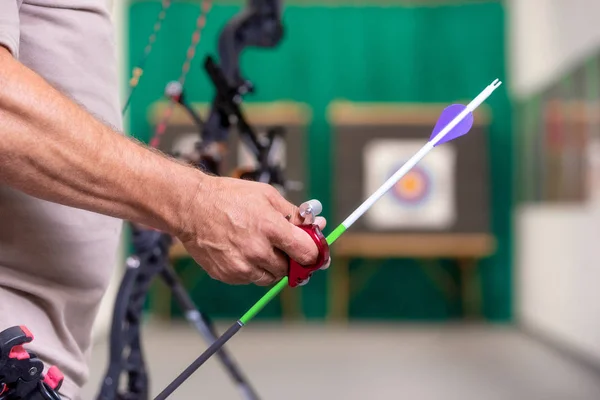 Archer sosteniendo arco recogiendo una flecha lista para disparar al blanco en el fondo. Vista trasera . —  Fotos de Stock