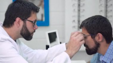 doktor oftalmolog oftalmolojik klinikte en uygun gözlük seçmek için bir müşteri yardımcı oluyor.