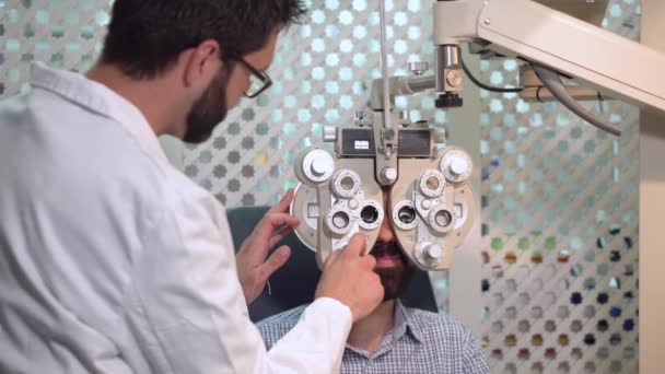 Οφθαλμίατρο που εξετάζει τον ασθενή με συσκευή οπτικής επιθεώρησης. Αρσενικό. Ασθενής να ελέγξει την όραση στην οφθαλμολογική κλινική. — Αρχείο Βίντεο