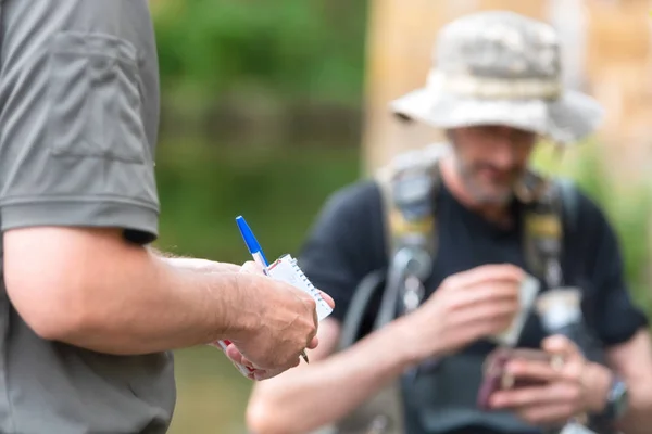 Офіцер поліції або Ranger перевірку рибалки ліцензії в річці. Риболовля інспекції. Закон. — стокове фото