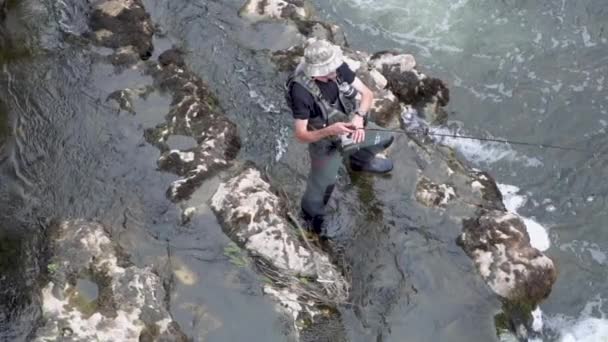 Vista aérea en cámara lenta del pescador pescando en un río con caña de pescar . — Vídeo de stock