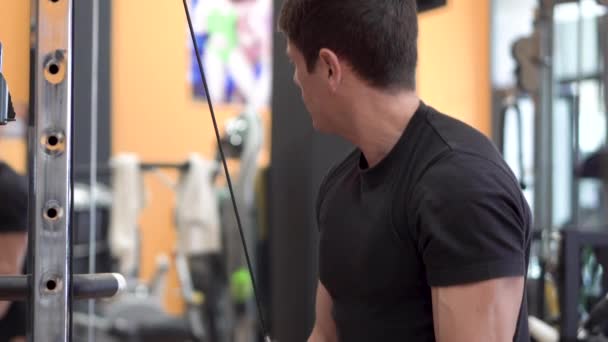 Jovem ajuste muscular homem fechar fazendo tríceps puxar para baixo corda extensão exercício no moderno centro de fitness . — Vídeo de Stock