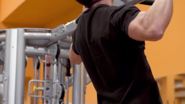 Спортсмен м'язиста фітнес-модель тягнеться на горизонтальний бар в спортзалі . — стокове відео