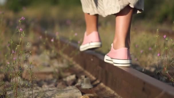 Chica caminando por el ferrocarril. Romántica toma de seguimiento en cámara lenta de pies de niña primer plano caminando a lo largo del ferrocarril en verano . — Vídeos de Stock