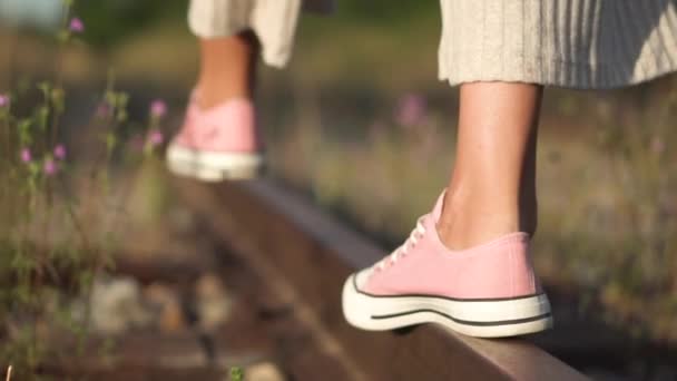 Fille marchant le long du chemin de fer. Plan romantique de suivi au ralenti de jeunes filles pieds gros plan marchant le long du rail de chemin de fer en été . — Video