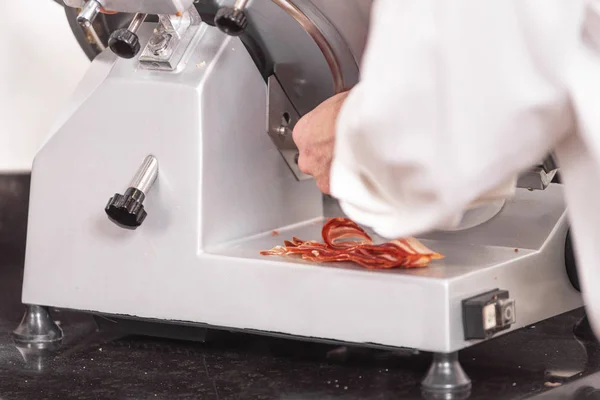 厨师使用火腿切片机。切片熏肉. — 图库照片