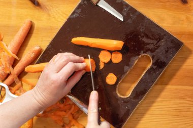 El tutma bıçağı ve ahşap tahta üzerinde havuç kesme.