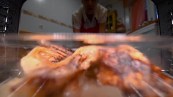 Mujer mayor tomando pollo asado del horno, visto desde el interior . — Vídeo de stock