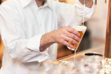 Müşteri için bira dolduruyorum. Barmen tezgahta dururken bira dolduruyor..