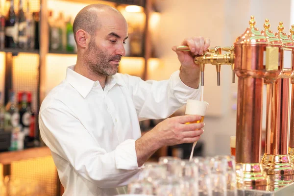 A servir cerveja para o cliente. Barman derramando cerveja enquanto estava no balcão do bar . — Fotografia de Stock