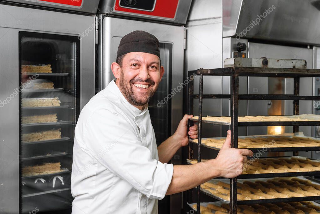 Baker Putting A Rack Of pastries Into Oven.
