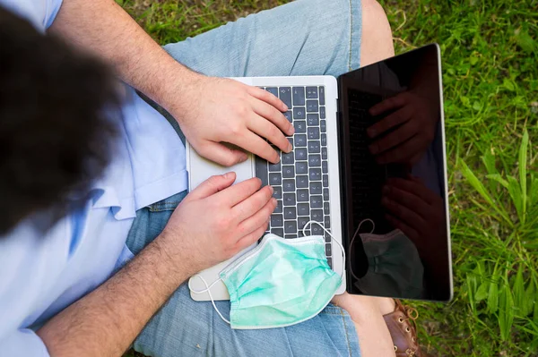 Man working with his laptop outdoors during Coronavirus pandemic. He has protective face mask. — Stock Photo, Image