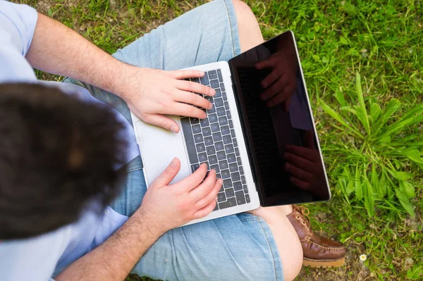 Unrecognizable man working with laptop sitting in the park. — Stock Photo, Image