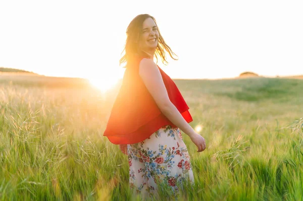 Cute girl w czerwonej sukience, śmiejąc się z radości na świeżym powietrzu w wiosennym zachodzie słońca. — Zdjęcie stockowe