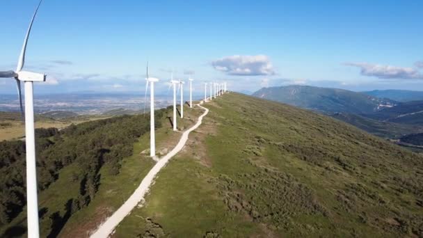 Vista aérea da fazenda de moinhos de vento para a produção de energia renovável no céu azul bonito. Turbinas eólicas geradoras de energia renovável limpa para o desenvolvimento sustentável — Vídeo de Stock